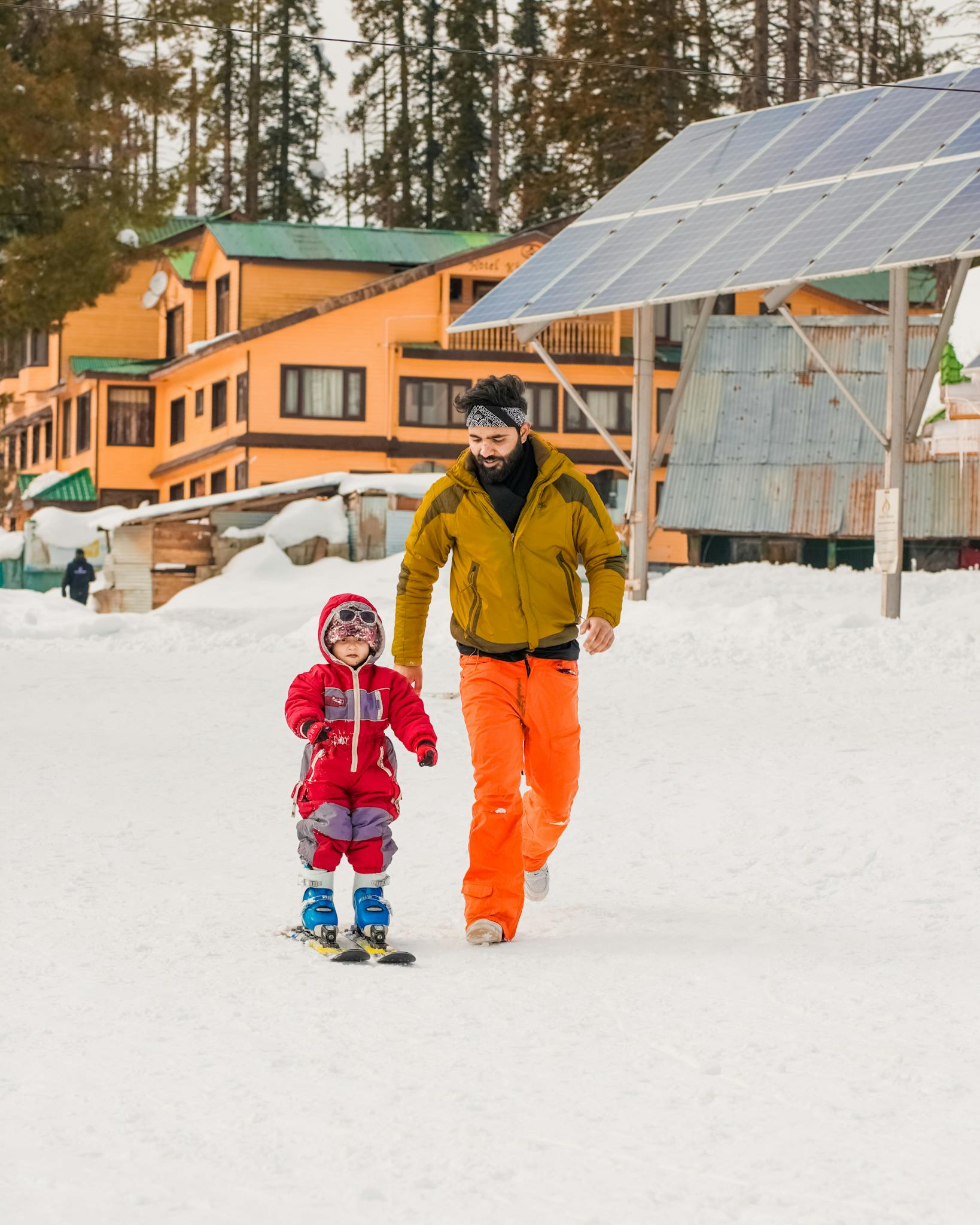 A father and child enjoying a skiing adventure on a snow-covered day with bright winter outfits.